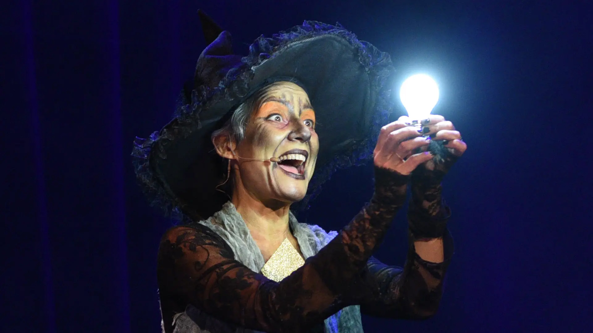 La sorcière tenant l'ampoule magique allumée, spectacle Le Bal des Fantômes.
